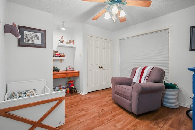 living area featuring a textured ceiling, ceiling fan, and light hardwood / wood-style floors