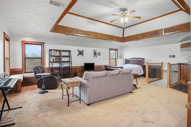 living room featuring ceiling fan, a tray ceiling, light carpet, and a textured ceiling