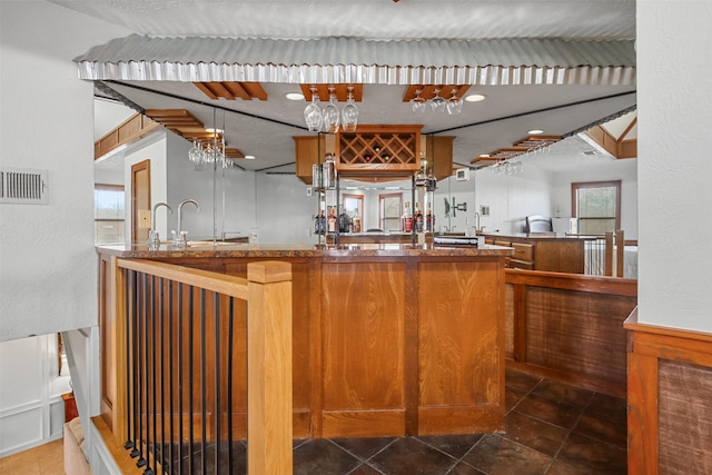 bar featuring sink, kitchen peninsula, and dark tile patterned flooring