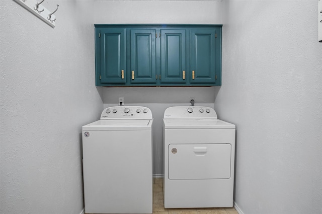 clothes washing area with separate washer and dryer and cabinets