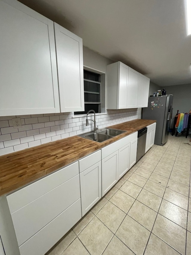 kitchen with appliances with stainless steel finishes, sink, butcher block countertops, and white cabinets