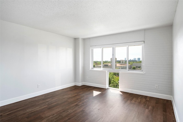 empty room featuring dark hardwood / wood-style floors and a textured ceiling