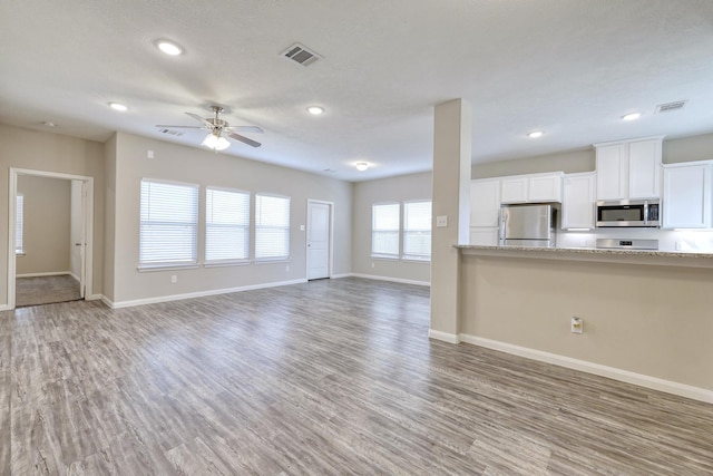 unfurnished living room featuring dark wood-type flooring and ceiling fan