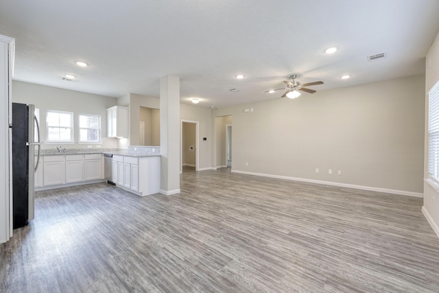 unfurnished living room featuring ceiling fan, sink, and light wood-type flooring