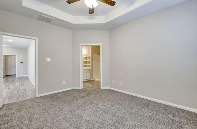 carpeted spare room featuring a tray ceiling and ceiling fan