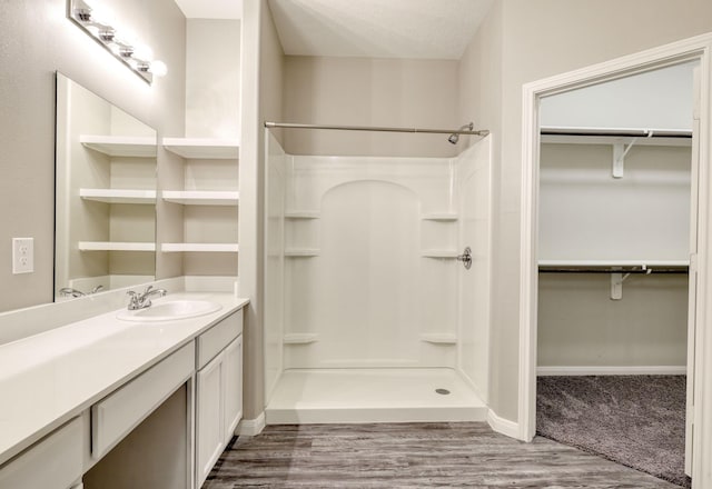 bathroom with a shower, hardwood / wood-style floors, vanity, and a textured ceiling