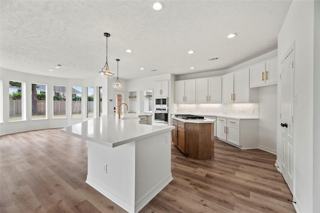 kitchen featuring a large island, pendant lighting, white cabinets, and appliances with stainless steel finishes