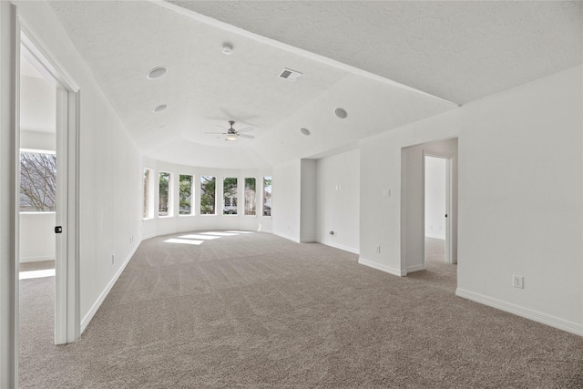 unfurnished living room with ceiling fan, light colored carpet, a tray ceiling, and a textured ceiling