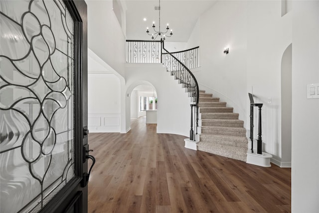 entrance foyer featuring hardwood / wood-style floors, a notable chandelier, and high vaulted ceiling