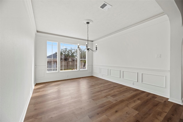 unfurnished dining area with wood-type flooring, crown molding, and a chandelier