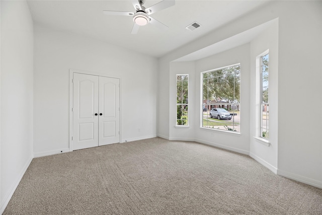 carpeted empty room featuring a wealth of natural light and ceiling fan