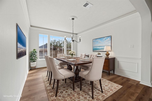 dining space with hardwood / wood-style flooring, ornamental molding, and a chandelier