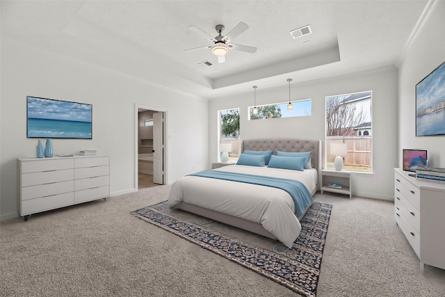 carpeted bedroom with multiple windows, ornamental molding, ceiling fan, and a tray ceiling