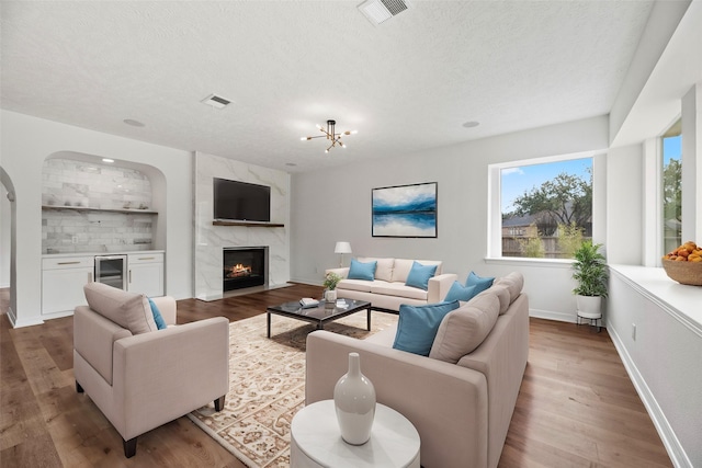 living room with a textured ceiling, a fireplace, light hardwood / wood-style floors, and bar area