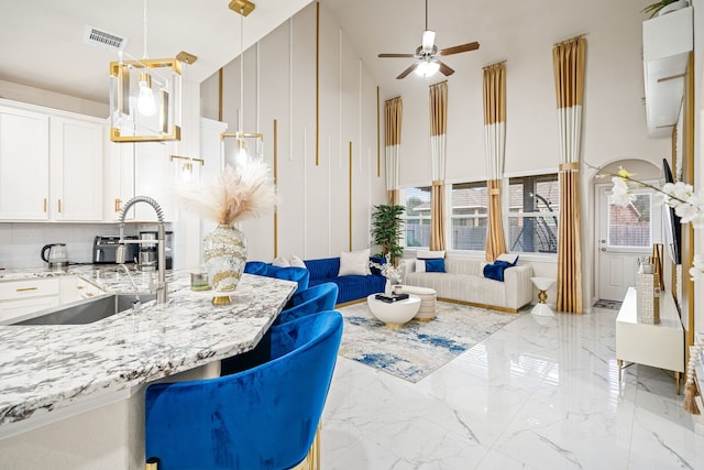 interior space featuring pendant lighting, a towering ceiling, sink, and white cabinets