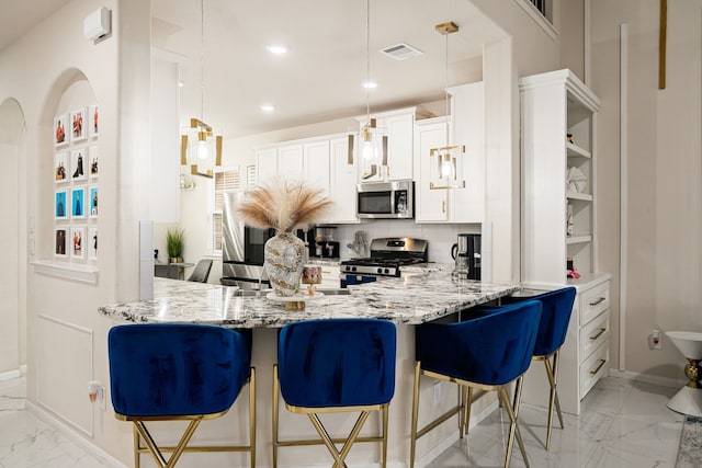 kitchen featuring pendant lighting, stainless steel appliances, a breakfast bar, and white cabinets