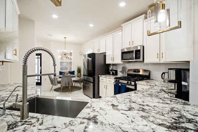 kitchen with white cabinetry, sink, hanging light fixtures, stainless steel appliances, and light stone countertops