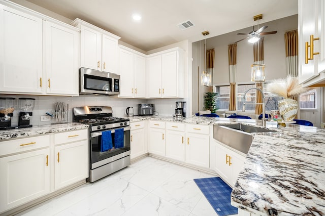 kitchen featuring sink, appliances with stainless steel finishes, light stone countertops, white cabinets, and decorative backsplash