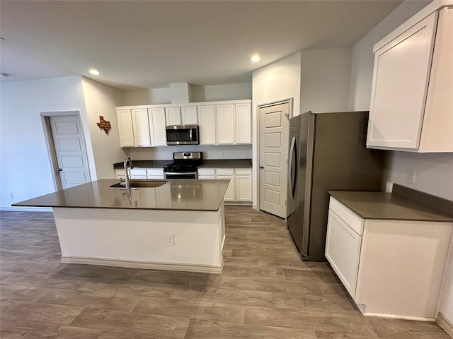 kitchen featuring sink, light hardwood / wood-style flooring, a center island with sink, stainless steel appliances, and white cabinets