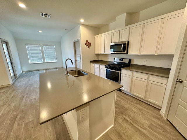 kitchen featuring a kitchen island with sink, sink, stainless steel appliances, and white cabinets