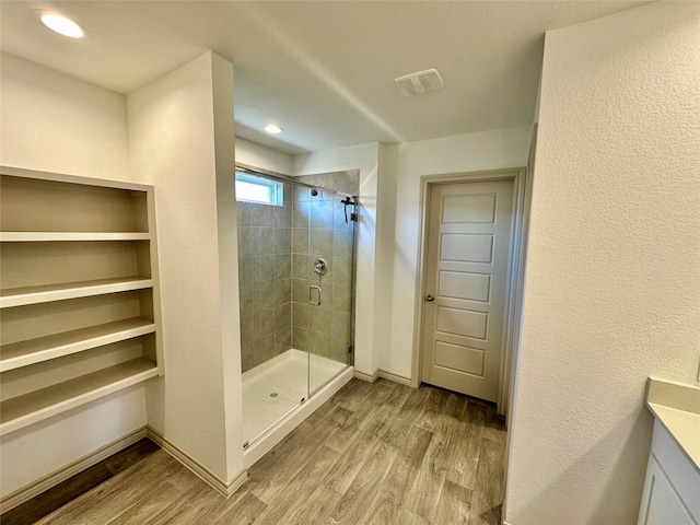 bathroom featuring wood-type flooring, vanity, and walk in shower