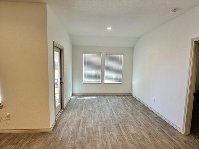 empty room with vaulted ceiling and light hardwood / wood-style flooring