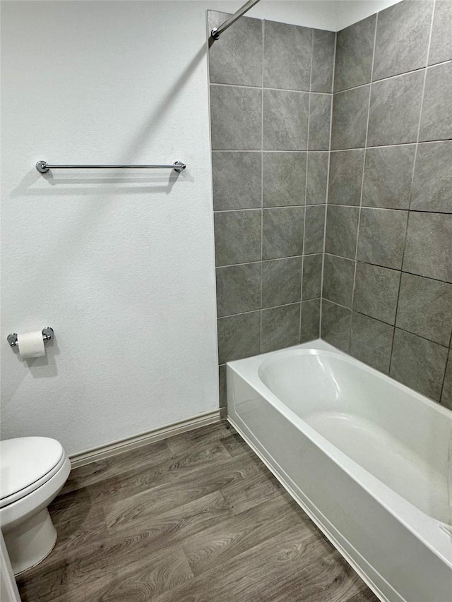 bathroom featuring tiled shower / bath combo, hardwood / wood-style floors, and toilet