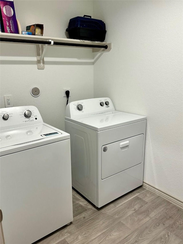 washroom with light hardwood / wood-style flooring and washer and dryer