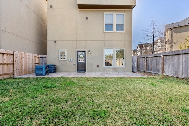 rear view of property with central AC unit, a patio area, and a lawn