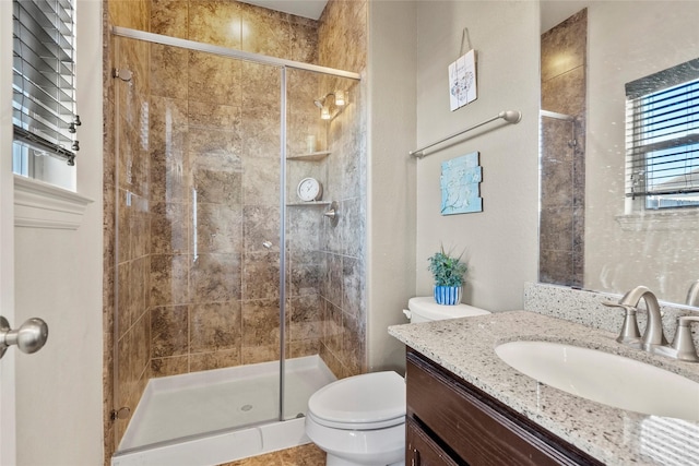 bathroom with toilet, vanity, and a shower with shower door