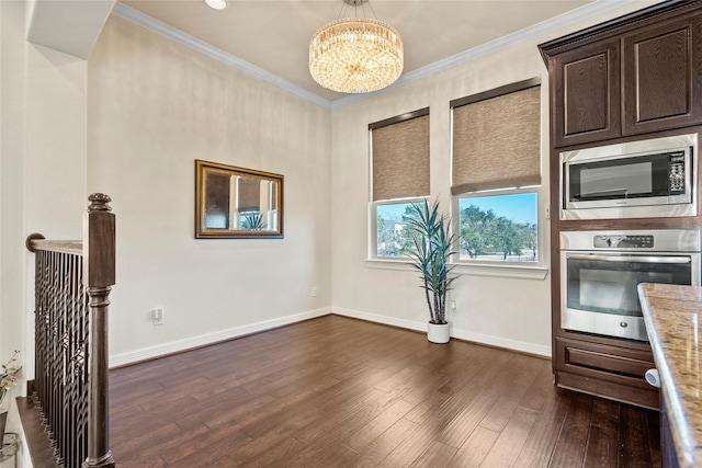 kitchen featuring dark wood-type flooring, appliances with stainless steel finishes, an inviting chandelier, light stone counters, and ornamental molding