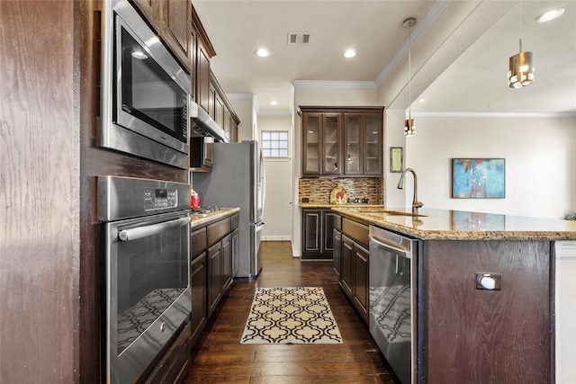 kitchen with pendant lighting, sink, crown molding, stainless steel appliances, and light stone countertops