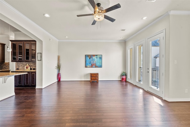 unfurnished living room featuring dark hardwood / wood-style flooring, ornamental molding, and ceiling fan