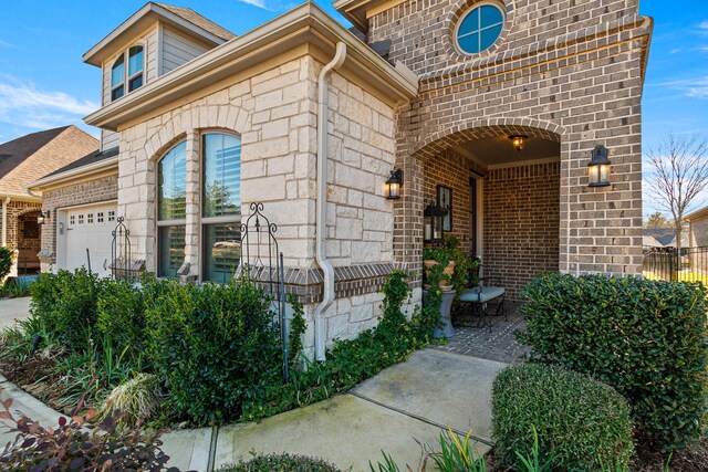 view of exterior entry with stone siding, brick siding, and an attached garage