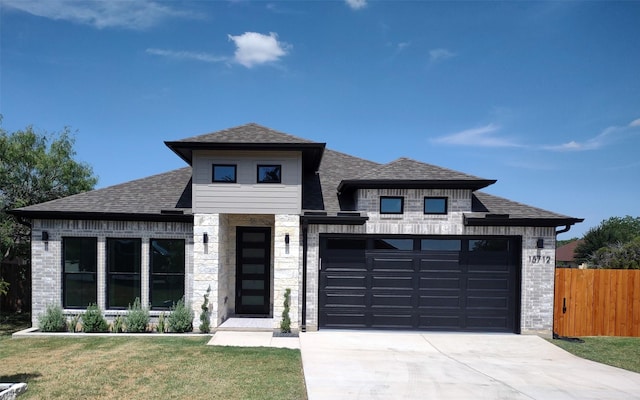 view of front of house featuring driveway, roof with shingles, an attached garage, a front lawn, and brick siding