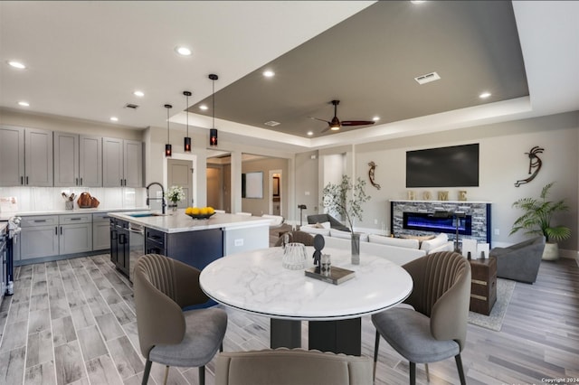 dining room with visible vents, a raised ceiling, a ceiling fan, and a glass covered fireplace