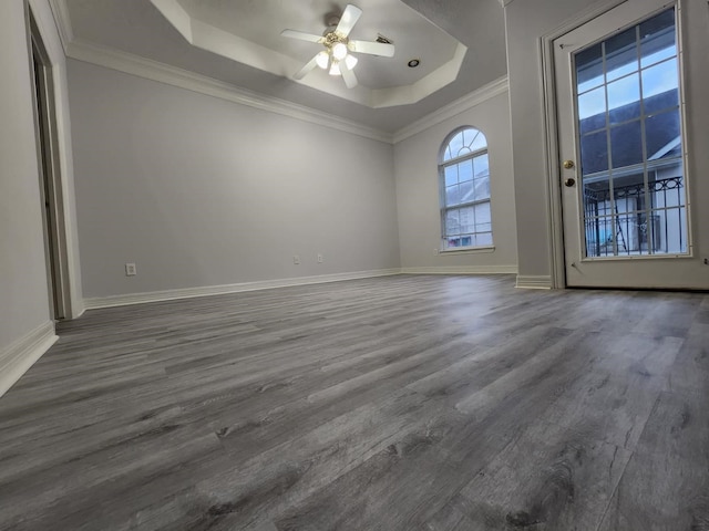 spare room with ceiling fan, ornamental molding, a tray ceiling, and dark hardwood / wood-style flooring