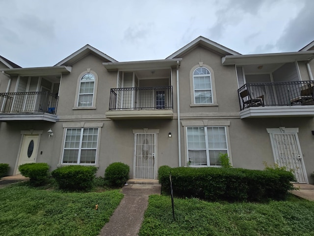 multi unit property with a front yard and a balcony