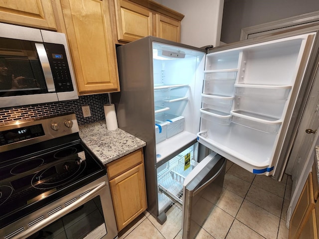 kitchen featuring stainless steel appliances, light stone countertops, light tile patterned floors, and backsplash