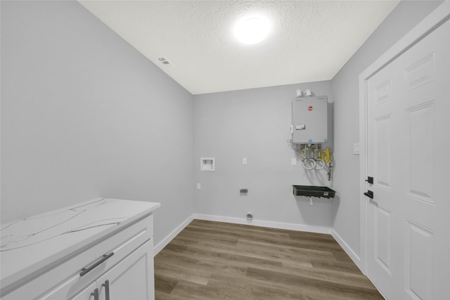 laundry room featuring light hardwood / wood-style flooring, hookup for a washing machine, tankless water heater, a textured ceiling, and hookup for an electric dryer