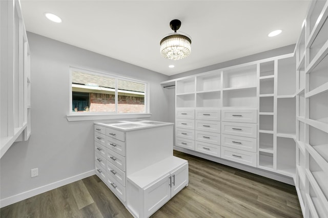 spacious closet with dark hardwood / wood-style floors and a chandelier