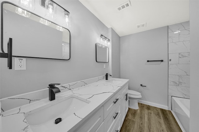 full bathroom with tiled shower / bath, wood-type flooring, toilet, and vanity