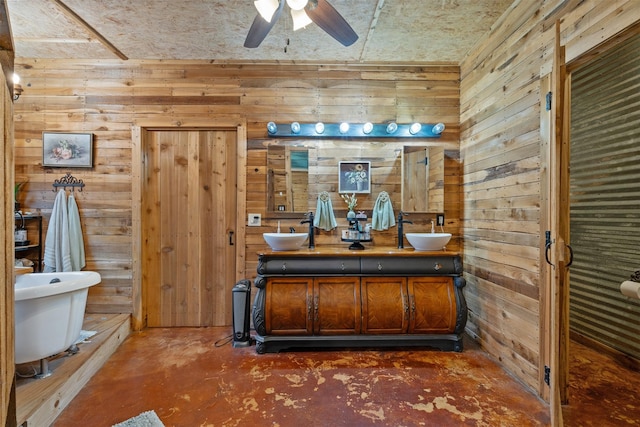 full bath with double vanity, a ceiling fan, a sink, wood walls, and a freestanding tub