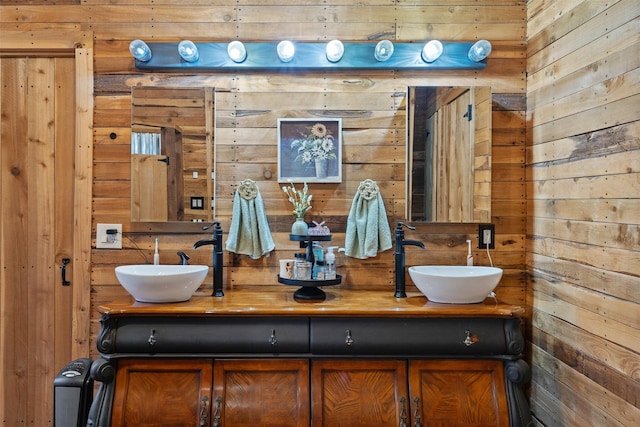 bathroom featuring a sink, wood walls, and double vanity