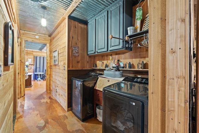 kitchen featuring decorative light fixtures, wood walls, and washing machine and clothes dryer