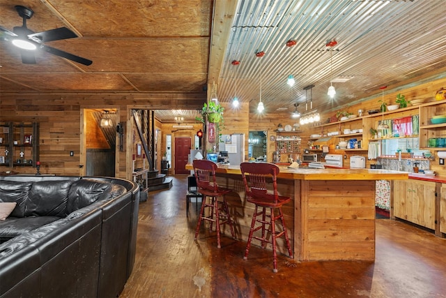 bar with dark wood-style floors, a ceiling fan, and wooden walls