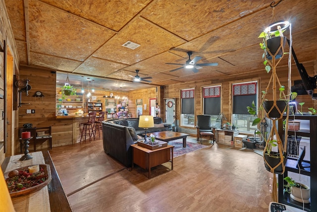 living room with a dry bar, wood walls, and visible vents