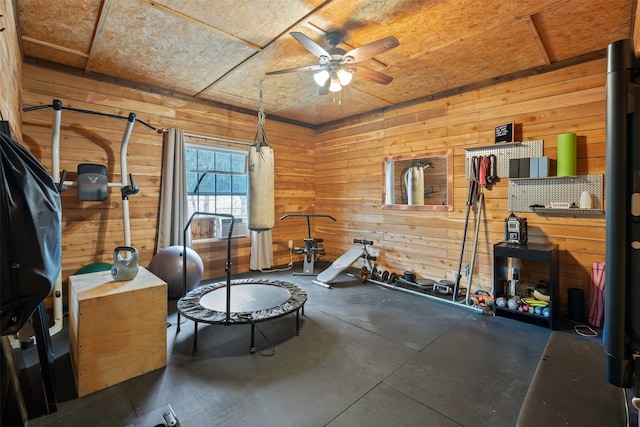 workout area with a ceiling fan and wooden walls