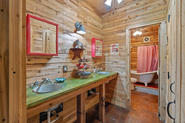 bathroom featuring ceiling fan, a freestanding bath, dual sinks, and toilet