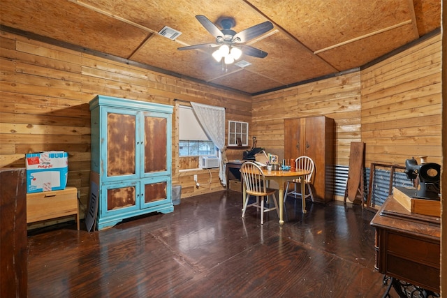 dining area featuring wooden walls, visible vents, a ceiling fan, dark wood-type flooring, and cooling unit